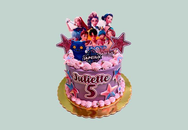 Detalle lateral de tarta temática KPop Demon Hunters con piezas comestibles de personajes y logo sobre acabado morado estrellado